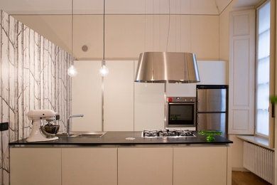 Esempio di una cucina design con lavello a doppia vasca, ante bianche, top in granito, elettrodomestici in acciaio inossidabile e parquet chiaro