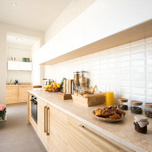 This is an example of a mid-sized scandinavian galley kitchen in Florence with flat-panel cabinets, light wood cabinets, limestone benchtops, white splashback and grey floor.