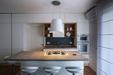 Foto di una cucina minimalista di medie dimensioni con lavello sottopiano, ante lisce, ante bianche, top in laminato, paraspruzzi grigio, elettrodomestici bianchi, parquet chiaro e top grigio