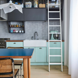Esempio di una cucina design di medie dimensioni con ante lisce, ante verdi, top in laminato, paraspruzzi grigio, paraspruzzi con piastrelle in ceramica, parquet chiaro, nessuna isola, top grigio, pavimento beige, lavello stile country e elettrodomestici neri
