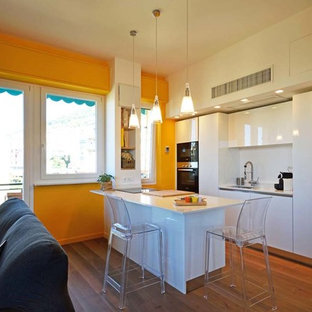 Idee per una cucina minimalista con lavello a vasca singola, ante lisce, ante bianche, paraspruzzi bianco, elettrodomestici bianchi, pavimento in laminato, penisola e top bianco