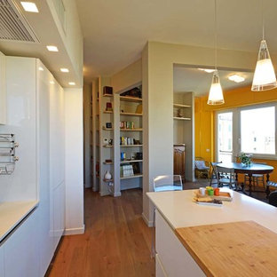 Esempio di una cucina minimalista con lavello a vasca singola, ante lisce, ante bianche, paraspruzzi bianco, elettrodomestici bianchi, pavimento in laminato, penisola e top bianco