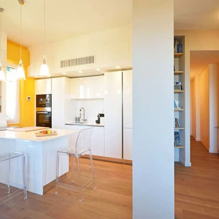 Esempio di una cucina minimalista con lavello a vasca singola, ante lisce, ante bianche, paraspruzzi bianco, elettrodomestici bianchi, pavimento in laminato, penisola e top bianco