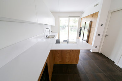 Esempio di una cucina minimalista di medie dimensioni con lavello sottopiano, ante lisce, ante con finitura invecchiata, top in quarzo composito, elettrodomestici in acciaio inossidabile e top bianco