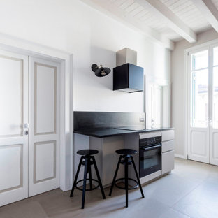 Foto di una cucina parallela contemporanea chiusa e di medie dimensioni con lavello sottopiano, ante beige, top in granito, paraspruzzi nero, paraspruzzi in granito, elettrodomestici neri, pavimento in gres porcellanato, isola, pavimento beige, top nero e travi a vista