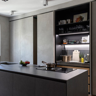 Esempio di un cucina con isola centrale design con ante lisce, ante grigie, pavimento in legno massello medio, pavimento marrone e top grigio