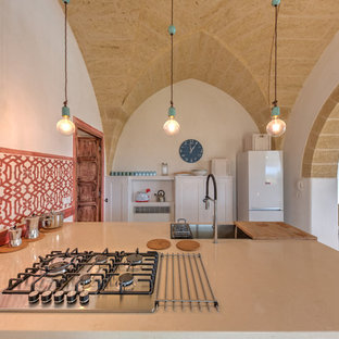 Foto di una cucina mediterranea con top beige, lavello da incasso, ante con riquadro incassato, ante bianche, paraspruzzi rosso, elettrodomestici bianchi, penisola e pavimento bianco
