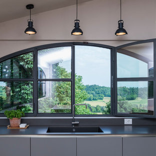 Immagine di un cucina con isola centrale country di medie dimensioni con lavello integrato, ante grigie, top in superficie solida, paraspruzzi grigio, top grigio e ante lisce