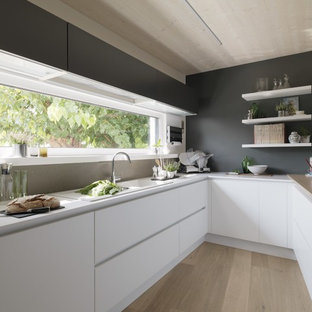 Idee per una cucina ad U minimal di medie dimensioni con lavello a doppia vasca, ante lisce, ante bianche, paraspruzzi grigio, elettrodomestici in acciaio inossidabile, parquet chiaro e penisola