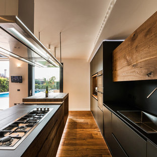 Design ideas for a contemporary open plan kitchen in Rome with a drop-in sink, medium wood cabinets, solid surface benchtops, black splashback, slate splashback, medium hardwood floors and with island.