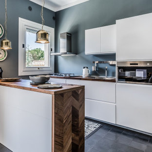 Ispirazione per una cucina parallela mediterranea con lavello da incasso, ante lisce, ante bianche, top in legno, elettrodomestici in acciaio inossidabile, penisola, pavimento nero e top marrone