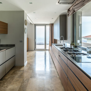 Immagine di una cucina parallela design con lavello integrato, ante lisce, ante grigie, top in acciaio inossidabile, paraspruzzi a finestra, nessuna isola e pavimento beige