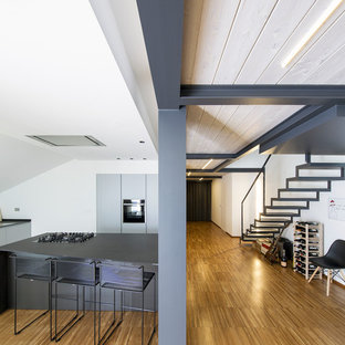 Ispirazione per un cucina con isola centrale design con ante lisce, ante grigie, elettrodomestici neri, pavimento in bambù e top grigio