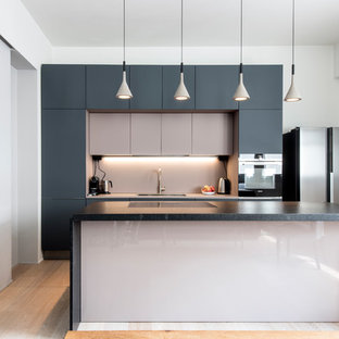 Idee per una grande cucina minimal con ante lisce, elettrodomestici neri, parquet chiaro, top nero, lavello da incasso, ante grigie, top in marmo, paraspruzzi rosa, paraspruzzi con lastra di vetro e pavimento beige
