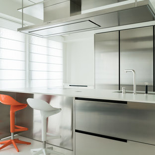Foto di una cucina parallela minimal con lavello sottopiano, ante in acciaio inossidabile, penisola, top bianco, ante lisce, paraspruzzi bianco, elettrodomestici in acciaio inossidabile e pavimento bianco