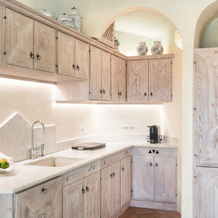 Esempio di una cucina a L mediterranea con ante in legno chiaro, paraspruzzi beige, lavello sottopiano, ante con riquadro incassato, paraspruzzi in lastra di pietra, pavimento in terracotta, nessuna isola, pavimento marrone e top beige