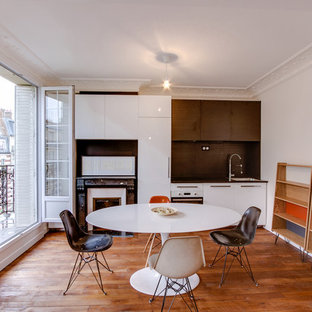 Idée de décoration pour une petite cuisine américaine linéaire design avec un placard à porte plane, des portes de placard blanches, une crédence blanche, un sol en bois foncé et aucun îlot.