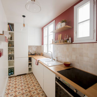 Design ideas for a mid-sized midcentury l-shaped separate kitchen in Paris with a double-bowl sink, white cabinets, wood benchtops, beige splashback, terra-cotta splashback, panelled appliances, cement tiles, no island, multi-coloured floor and brown benchtop.