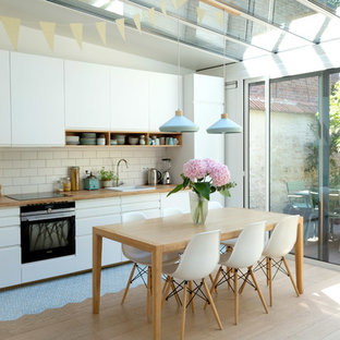 Idées déco pour une cuisine américaine linéaire scandinave de taille moyenne avec un placard à porte plane, des portes de placard blanches, un plan de travail en bois, une crédence blanche, une crédence en carreau de céramique, un électroménager encastrable, un sol en carreaux de ciment, aucun îlot, un évier posé et un sol bleu.