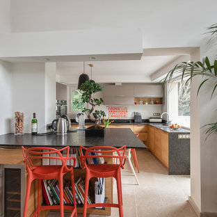 Réalisation d'une grand cuisine design en U avec un évier encastré, un placard à porte plane, des portes de placard en bois brun, une crédence blanche, une crédence en fenêtre, un électroménager en acier inoxydable, un sol beige et un plan de travail noir.