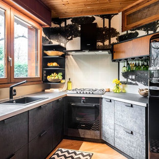 Réalisation d'une petit cuisine design avec des portes de placard noires, un plan de travail en stratifié, un évier posé, un placard à porte plane, une crédence grise, un électroménager noir, un sol en bois brun et un sol orange.