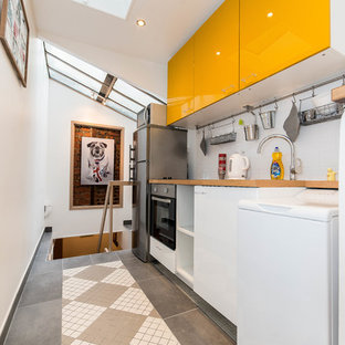 Idée de décoration pour une petit cuisine ouverte linéaire design avec un placard à porte plane, des portes de placard jaunes, un plan de travail en bois, une crédence blanche et aucun îlot.