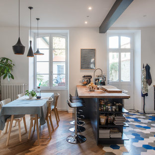 Exemple d'une cuisine américaine scandinave en L avec un placard avec porte à panneau surélevé, des portes de placard bleues, un plan de travail en bois, une crédence blanche, une crédence en carrelage métro, un électroménager en acier inoxydable, une péninsule, un sol multicolore et un plan de travail marron.