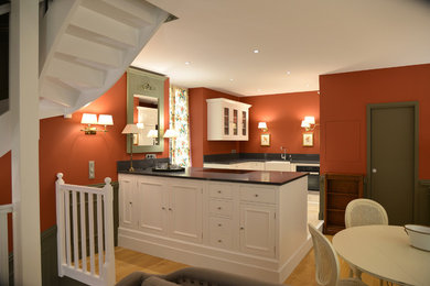 На фото: угловая кухня-гостиная среднего размера в стиле неоклассика (современная классика) с монолитной мойкой, красным фартуком, полом из терракотовой плитки и бежевым полом с