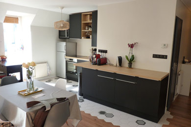This is an example of a medium sized contemporary l-shaped open plan kitchen in Rennes with a submerged sink, flat-panel cabinets, black cabinets, wood worktops, pink splashback, stainless steel appliances, ceramic flooring, no island, white floors and brown worktops.