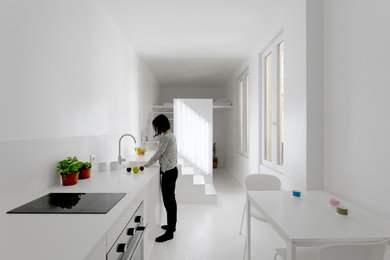 Modelo de cocina actual pequeña con fregadero integrado, puertas de armario blancas, encimera de acrílico, salpicadero blanco y electrodomésticos negros