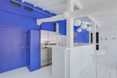 Photo of a contemporary u-shaped kitchen in Nice with flat-panel cabinets, white cabinets, white splashback, stainless steel appliances, painted wood flooring, white floors and white worktops.