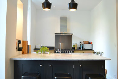 Cette photo montre une cuisine ouverte parallèle craftsman de taille moyenne avec un évier intégré, des portes de placard noires et un sol en carrelage de céramique.