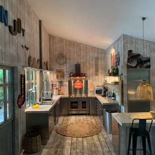 Exemple d'une grand cuisine ouverte montagne en U avec un évier posé, un placard à porte plane, une façade en inox, une crédence grise, une crédence en dalle métallique, un électroménager en acier inoxydable, un sol en bois brun, un îlot central, un sol gris et un plan de travail gris.