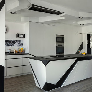 Inspiration pour une grand cuisine ouverte design en L avec un placard à porte plane, un îlot central, un évier 2 bacs, une crédence blanche, un électroménager en acier inoxydable, un sol en bois peint, un sol gris et un plan de travail noir.