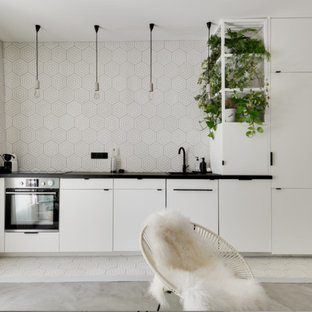 Aménagement d'un salon avec une bibliothèque ou un coin lecture scandinave de taille moyenne et ouvert avec un mur blanc, béton au sol, aucune cheminée, un sol gris et un téléviseur dissimulé.