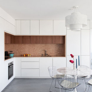 Aménagement d'une cuisine américaine contemporaine en L de taille moyenne avec un évier intégré, un placard à porte affleurante, des portes de placard blanches, un plan de travail en marbre, une crédence rose, une crédence en marbre, un électroménager encastrable, béton au sol, un sol gris, un plan de travail rose et aucun îlot.