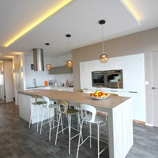 This is an example of a mid-sized contemporary u-shaped eat-in kitchen in Lyon with an undermount sink, white cabinets, laminate benchtops, white splashback, stainless steel appliances, laminate floors, with island, beige benchtop, flat-panel cabinets, glass sheet splashback and grey floor.