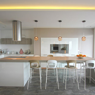 Idée de décoration pour une cuisine américaine beige et marron design en U de taille moyenne avec des portes de placard blanches, une crédence blanche, une crédence en feuille de verre, un électroménager en acier inoxydable, un îlot central, un placard à porte plane, un évier encastré, un plan de travail en stratifié, sol en stratifié, un plan de travail beige et un sol gris.