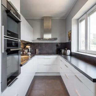 Exemple d'une cuisine tendance en L de taille moyenne et fermée avec un placard à porte plane, des portes de placard blanches et un électroménager en acier inoxydable.