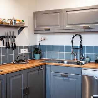 Idée de décoration pour une cuisine tradition en L fermée et de taille moyenne avec un évier 2 bacs, un placard avec porte à panneau surélevé, des portes de placard grises, un plan de travail en bois, une crédence bleue, un électroménager en acier inoxydable et aucun îlot.