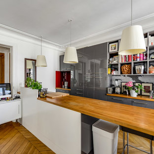 Idées déco pour une cuisine ouverte parallèle contemporaine avec un placard à porte plane, des portes de placard grises, un plan de travail en bois, une crédence multicolore, un sol en bois brun, un îlot central et un sol jaune.