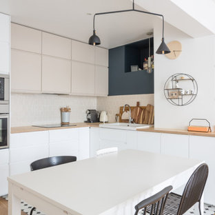 Exemple d'une grand cuisine ouverte scandinave en L avec un évier 1 bac, un placard à porte affleurante, des portes de placard blanches, un plan de travail en bois, une crédence beige, une crédence en carreau de terre cuite, un électroménager en acier inoxydable, un sol en carrelage de porcelaine, aucun îlot, un sol multicolore et un plan de travail beige.