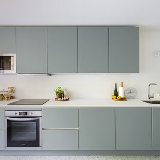 Diseño de cocina lineal, minimalista, de tamaño medio, abierta, sin isla, con fregadero bajoencimera, armarios con paneles lisos, puertas de armario grises, encimera de cuarcita, salpicadero blanco, salpicadero de losas de piedra, electrodomésticos de acero inoxidable, suelo de terrazo, suelo beige y encimeras blancas
