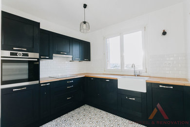 パリにある高級な中くらいなミッドセンチュリースタイルのおしゃれなキッチン (エプロンフロントシンク、ルーバー扉のキャビネット、青いキャビネット、木材カウンター、白いキッチンパネル、サブウェイタイルのキッチンパネル、パネルと同色の調理設備、セメントタイルの床、アイランドなし、白い床) の写真