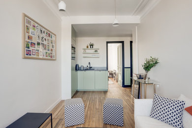 Réalisation d'une cuisine ouverte tradition en L avec un évier 1 bac, un placard à porte affleurante, des portes de placards vertess, une crédence grise, un électroménager noir, un sol en bois brun, aucun îlot et un plan de travail gris.