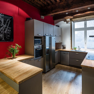 Cette photo montre une cuisine américaine tendance en U de taille moyenne avec des portes de placard grises et une péninsule.