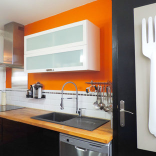 Idées déco pour une cuisine linéaire contemporaine fermée et de taille moyenne avec un évier posé, des portes de placard noires, un plan de travail en bois, une crédence blanche, une crédence en carrelage métro, un électroménager en acier inoxydable et aucun îlot.