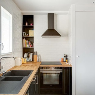 Idée de décoration pour une petite cuisine design en L avec un évier 2 bacs, un plan de travail en bois, une crédence blanche, une crédence en carrelage métro, aucun îlot, un placard à porte plane, des portes de placard blanches et un électroménager noir.