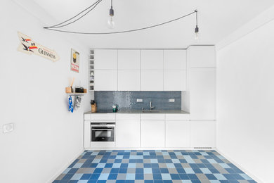 Cette image montre une petite cuisine américaine linéaire et encastrable design avec un évier encastré, une crédence bleue, une crédence en mosaïque et un sol en carrelage de céramique.