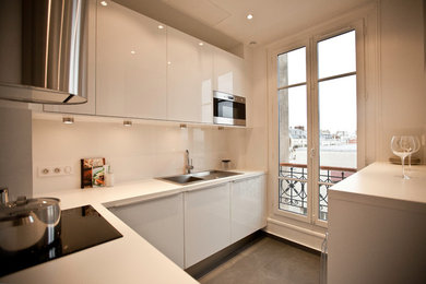 パリにある高級な小さなコンテンポラリースタイルのおしゃれなキッチン (シングルシンク、インセット扉のキャビネット、白いキャビネット、ラミネートカウンター、白いキッチンパネル、セラミックタイルのキッチンパネル、シルバーの調理設備、セラミックタイルの床) の写真